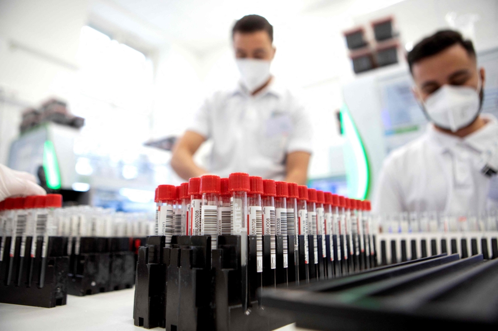 ممرضون يقومون بفحص محلول الغرغرة لفيروس كورونا في مختبر بفيينا في 1 فبراير الجاري. (أ ف ب)