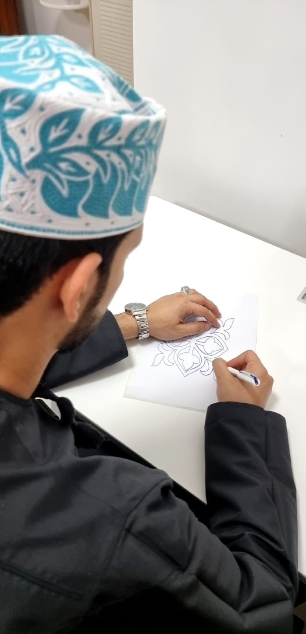 الهنائي خلال تصميمه للكميم العمانية