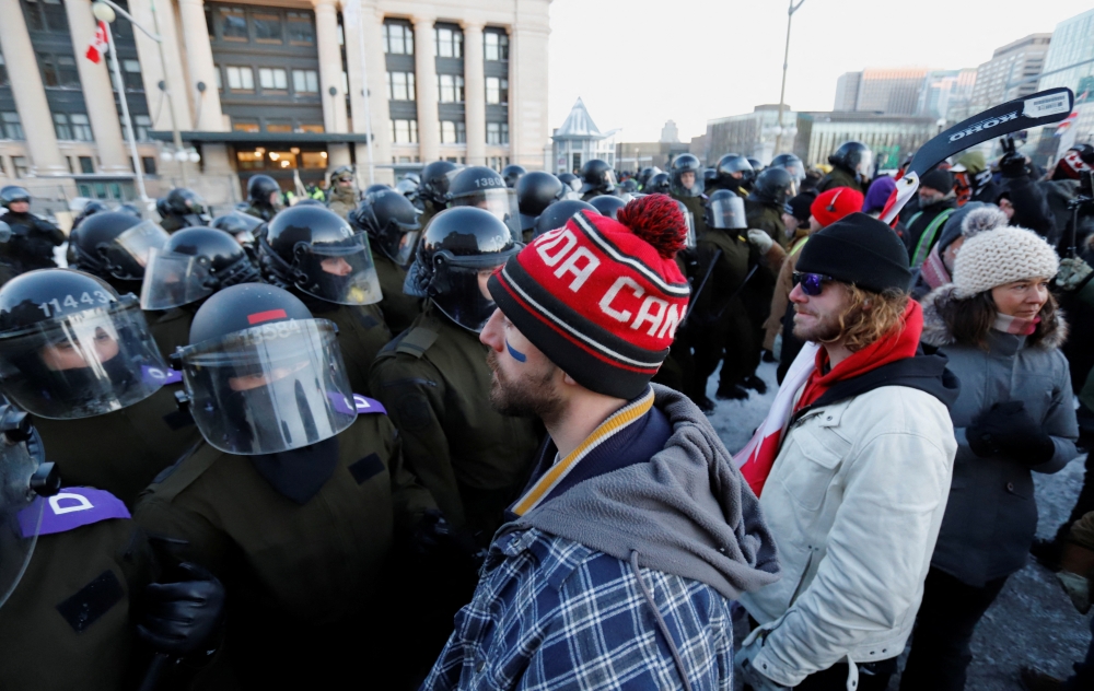 أشخاص يواجهون الشرطة بينما يواصل سائقو الشاحنات وأنصارهم الاحتجاج على تفويضات لقاح فيروس كورونا في أوتاوا بكندا. "رويترز"  