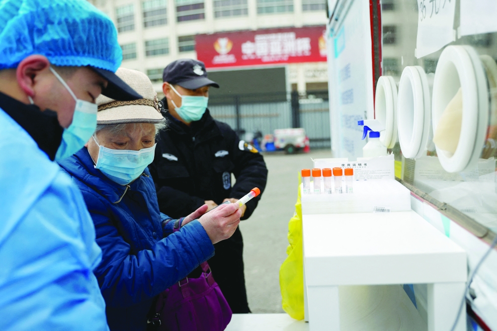 امرأة تحمل عينة قبل إجراء اختبار فيروس كورونا في موقع متنقل بأحد شوارع بكين