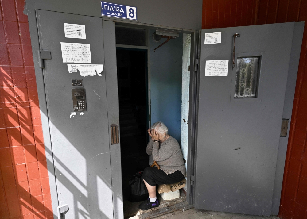  تبكي  جالينا تشورنا، 75 عامًا، وهي تجلس في مدخل مبنى مكون من تسعة طوابق متضرر حيث تعيش في سالتيفكا حيث دمرت الضربة الصاروخية الشقق فوق منزلها، وتحطمت نوافذها وبابها.أ.ف.ب 