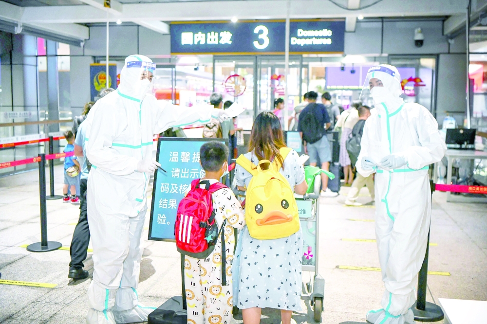 موظفين في احدى المطارات الصنية يقومون بتقديم الاختبارات المجانية للمسافرين بعد أن اعلنت شنجهاي تمديد الزام الفحوصات الاسبوعية حتى نهاية سبتمبر المقبل