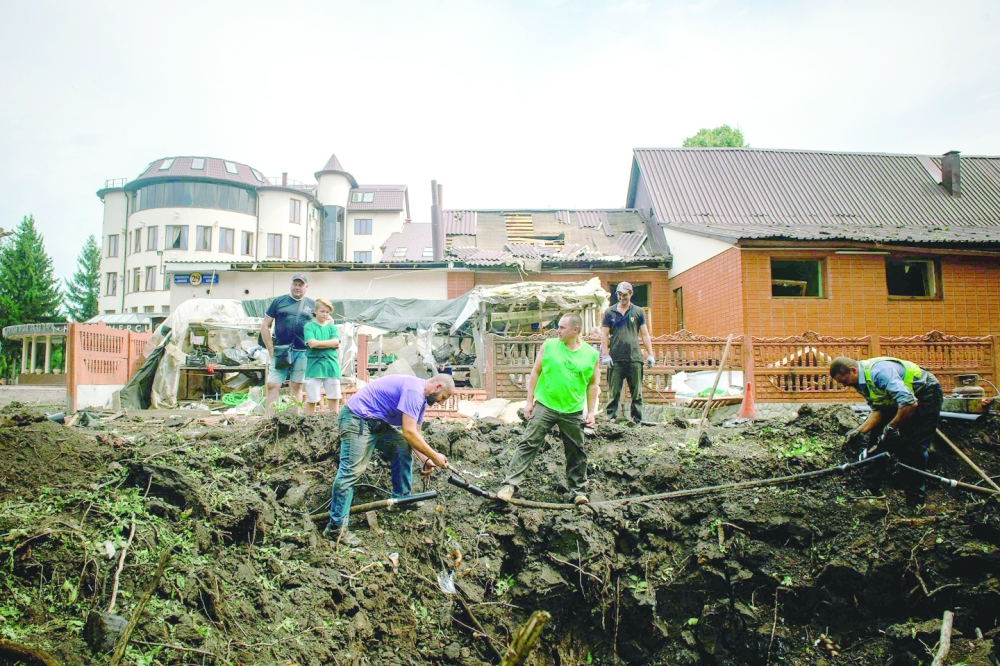 عمال الخدمة المجتمعية يعملون في حفرة بعد هجوم صاروخي على ثاني أكبر مدينة أوكرانية في خاركيف 