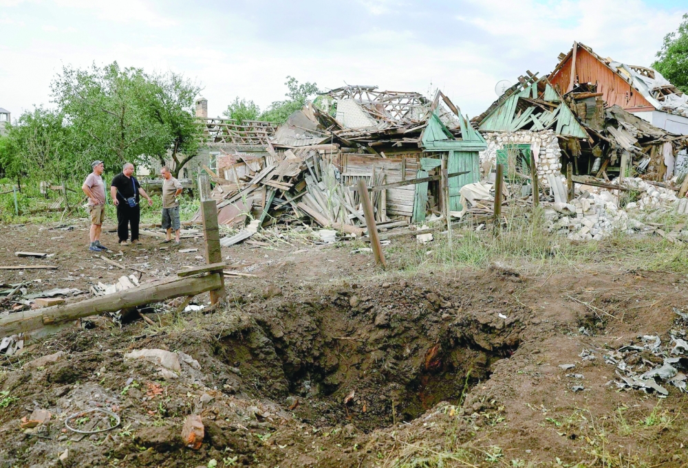 سكان محليون يقفون بجوار المباني المدمرة في أعقاب هجوم صاروخي على بلدة كراماتورسك في منطقة دونيتسك وسط الغزو العسكري الروسي لأوكرانيا