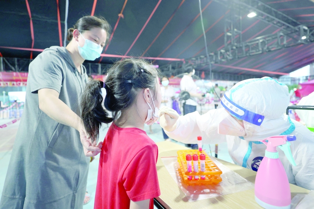 عاملًا صحيًا يجري مسحة لطفلة لتاكد من عدم اصابتها بفيروس كورونا في شيامن بمقاطعة فوجيان بشرق الصين