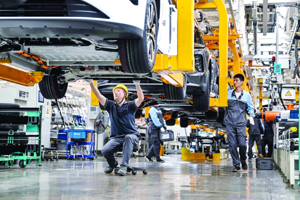موظف يتحقق من أسفل سيارة على طول خط التجميع في مصنع لشركة صناعة السيارات الصينية شرقي الصين. «أ.ف.ب»