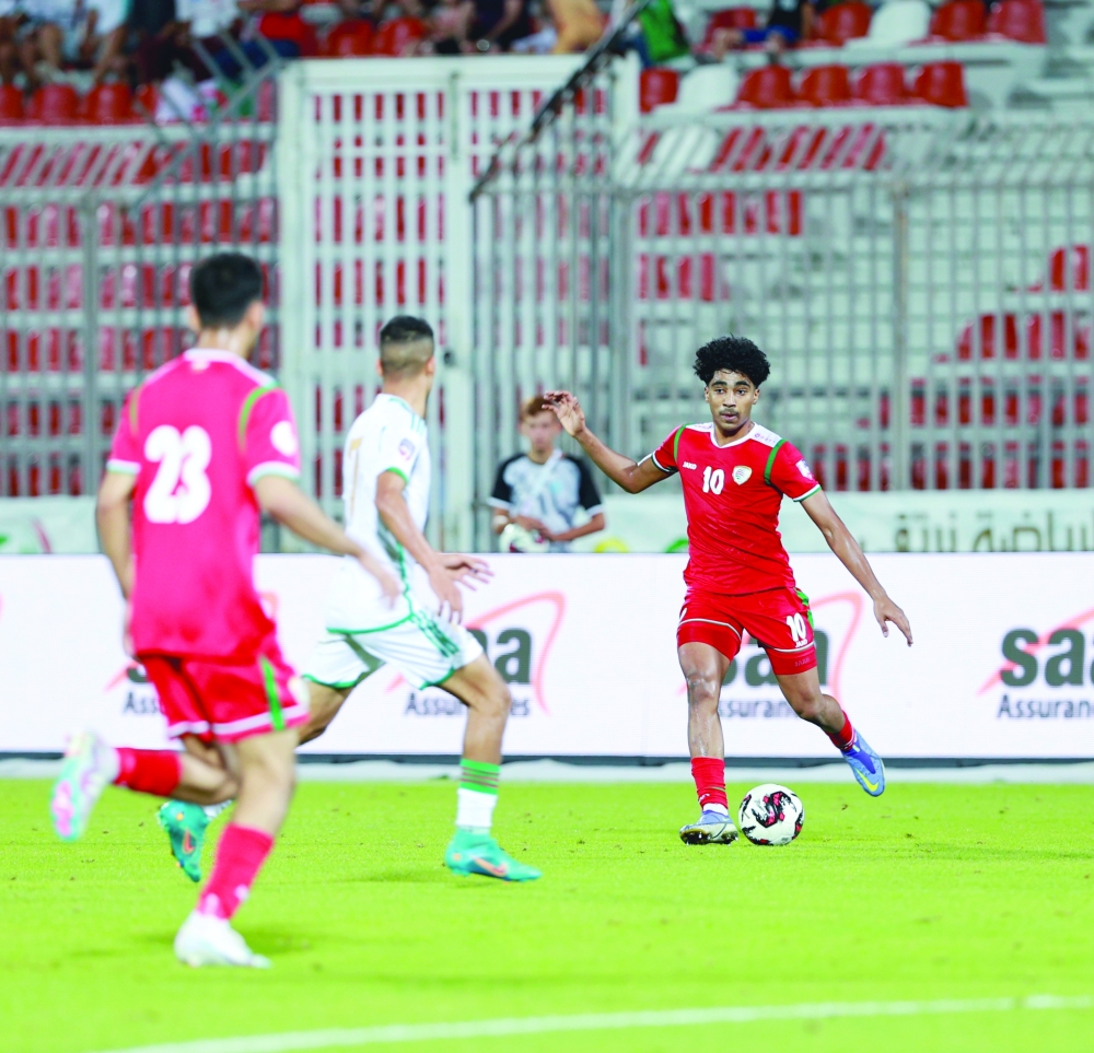 لاعب منتخبنا عبدالمجيد البلوشي يسدد الكرة وسط متابعة من لاعب منتخب الجزائر