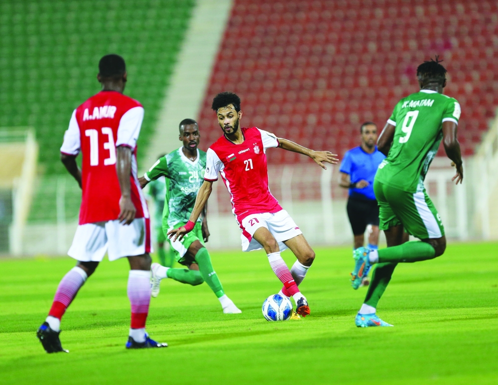 لاعب ظفار يحاول المرور من كمين لاعبي صحار في اللقاء تصوير: أحمد البريكي