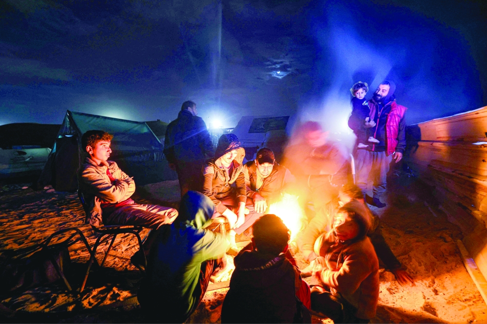 نازحون فلسطينيون يتدفئون بالنيران في مخيم مؤقت غرب رفح بالقرب من الحدود المصرية. أ.ف.ب 
