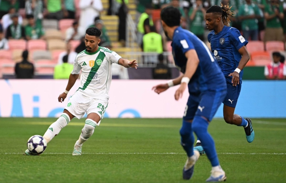 لاعب الأهلي السعودي يمرر الكرة وسط مراقبة من لاعبا الدحيل
